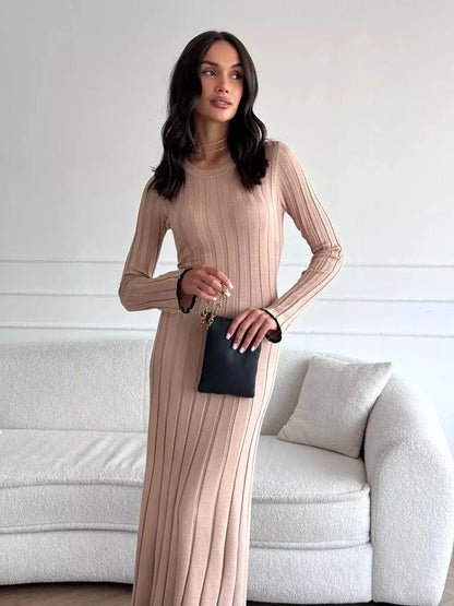 Model wearing the Sahara Curve Maxi Dress in sandstone beige, showcasing its soft ribbed texture and elegant full-length design.