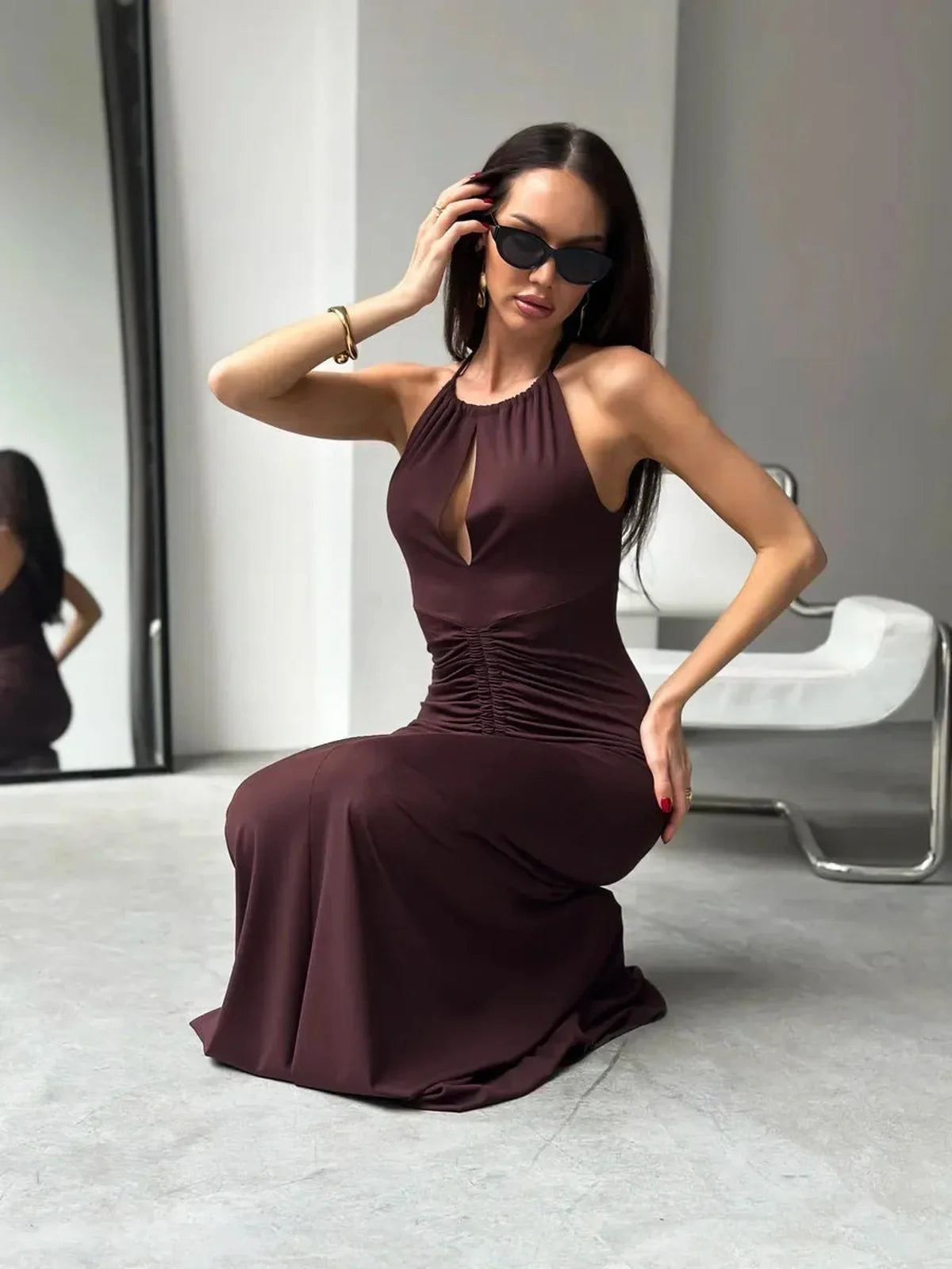 Model wearing a sleek Maxi Dress Sienna in rich sienna hue, showcasing halter neckline and ruched design.