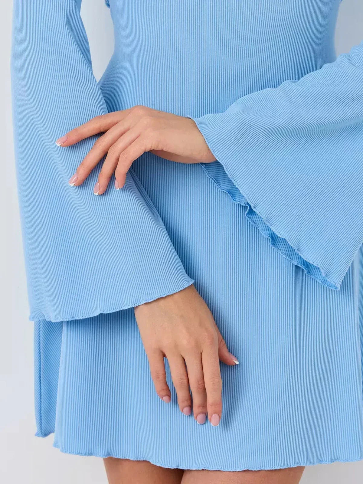 Close-up of pastel blue ribbed knit mini dress showcasing flared sleeves and elegant silhouette.