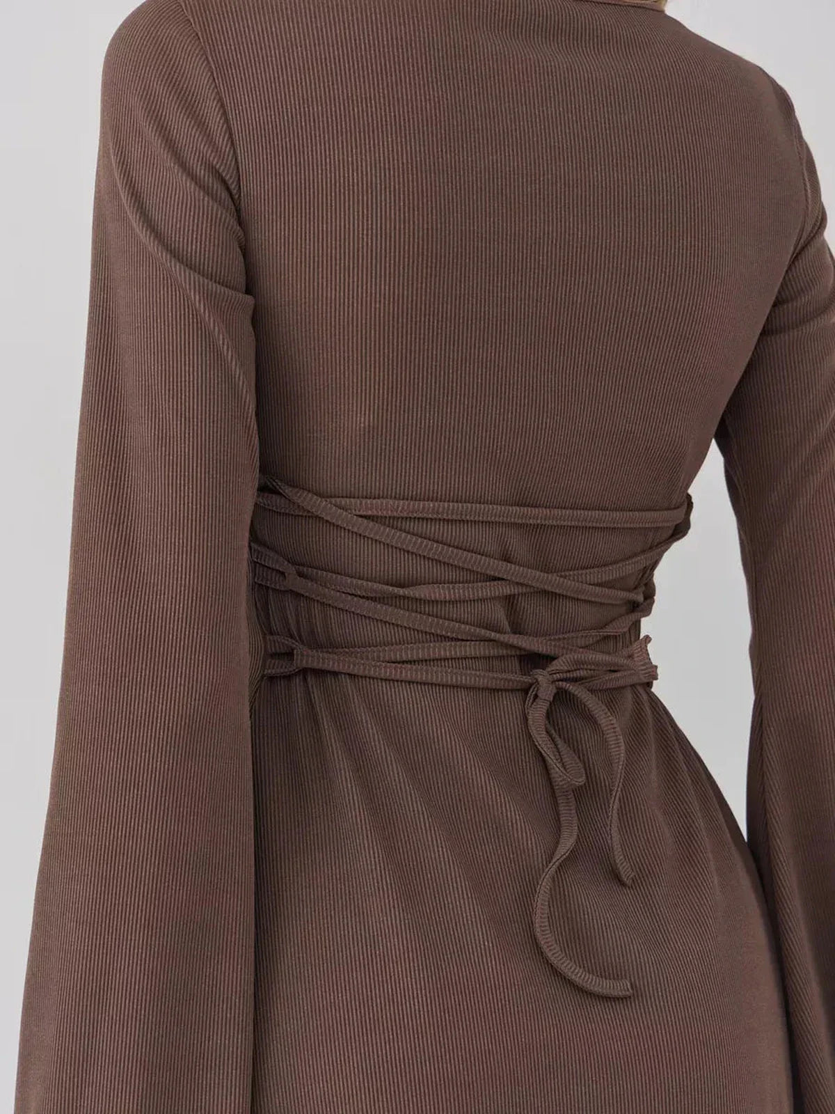 Back view of a brown ribbed mini dress featuring flared cuffs and figure-defining waist ties.