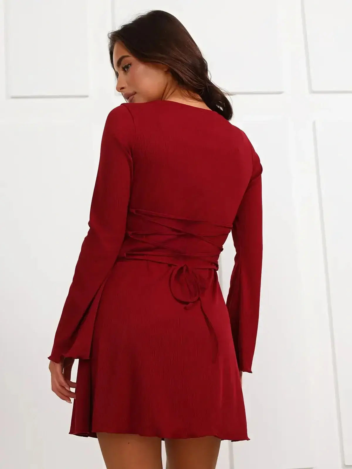 Back view of a red mini dress with corset lace-up detail and long sleeves, perfect for weddings and parties.