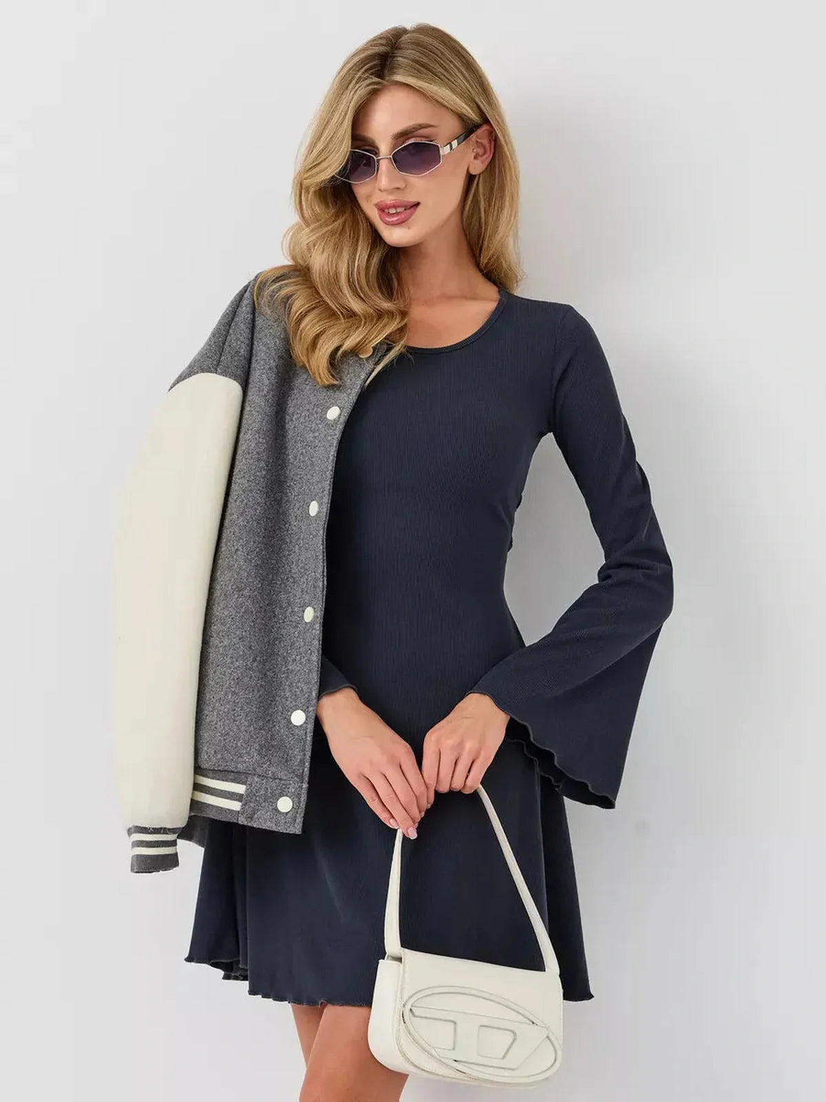 Model wearing the Graphite Grace mini dress with bell sleeves and a stylish jacket, embodying chic elegance.