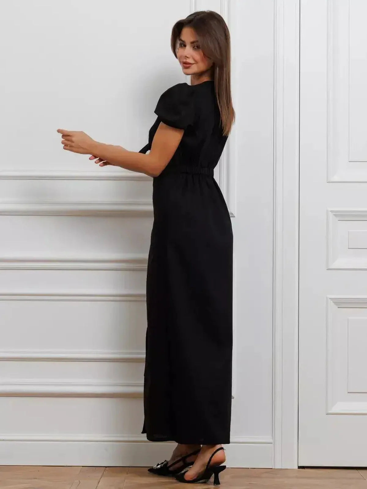 Elegant woman in a black maxi dress with puff sleeves and tie-front detail, showcasing a refined silhouette.