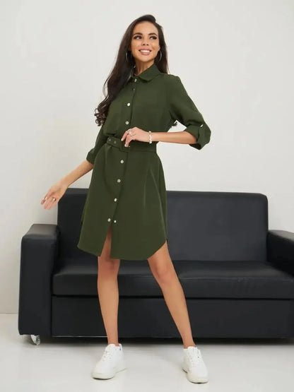 Model wearing an olive green belted shirt mini dress, showcasing a relaxed silhouette and polished snap-button front.