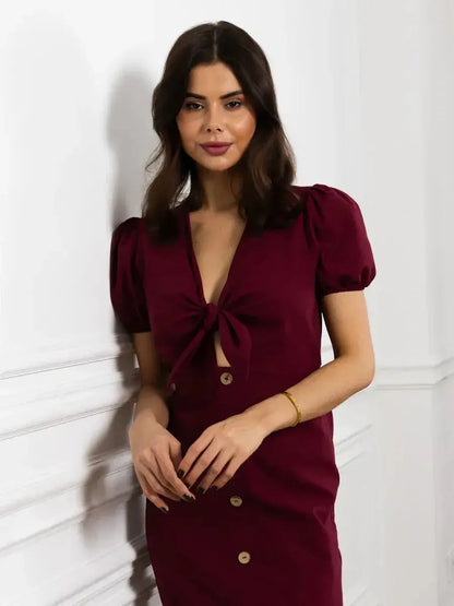 Model wearing a burgundy maxi dress with a front bow, deep V-neck, and puff sleeves, showcasing elegance and style.