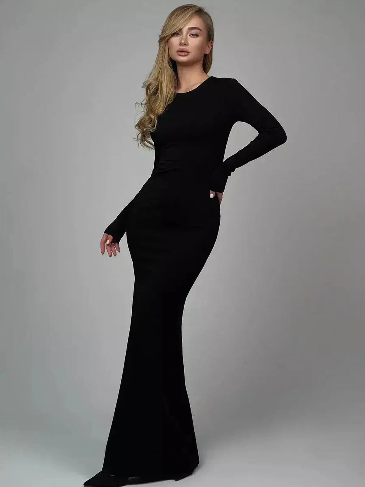 Model showcasing the Sculpted Elegance Maxi Dress in black, featuring long sleeves and a fitted silhouette.