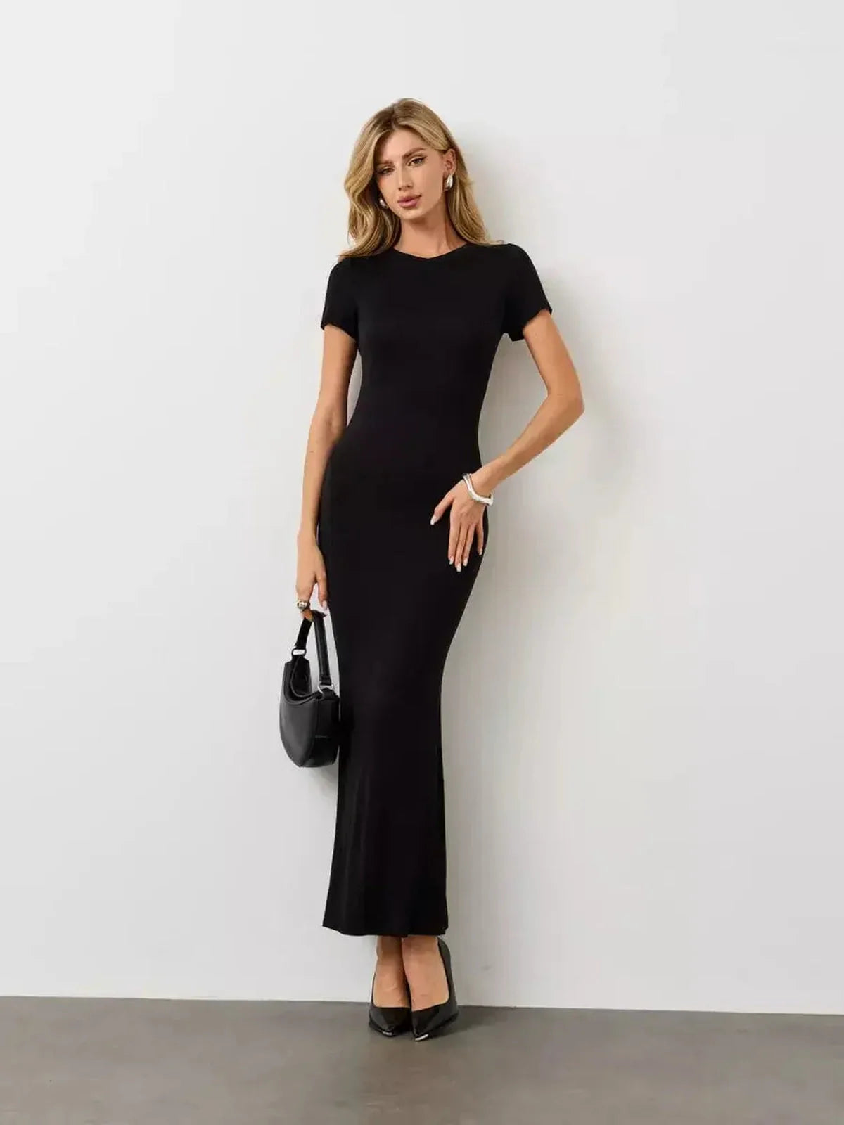 Model wearing a sleek Noir Curve Maxi Dress in black, showcasing its sculpted silhouette and minimalist design.