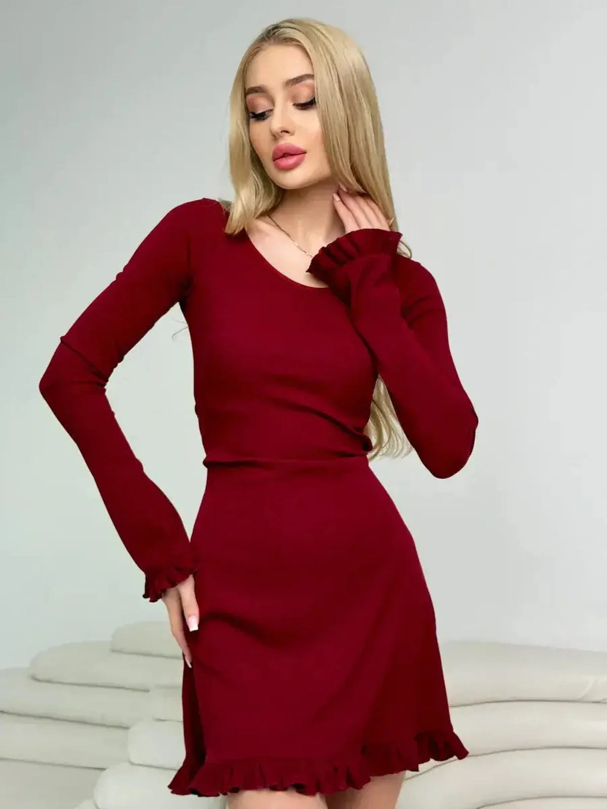 Model wearing the Crimson Flare red ribbed knit mini dress with romantic ruffles and a fitted silhouette.