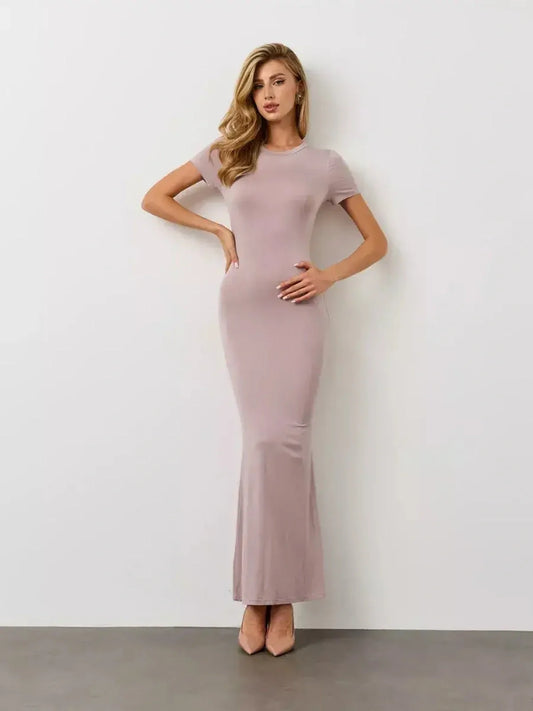 Model showcasing the Bare Essence Maxi Dress in soft beige, featuring a U-neckline and flared hem, embodying elegance.