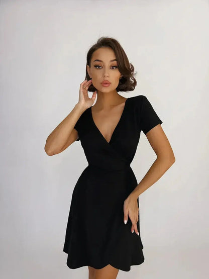 Model showcasing a sleek black mini dress with a deep V-neckline and fitted wrap design.