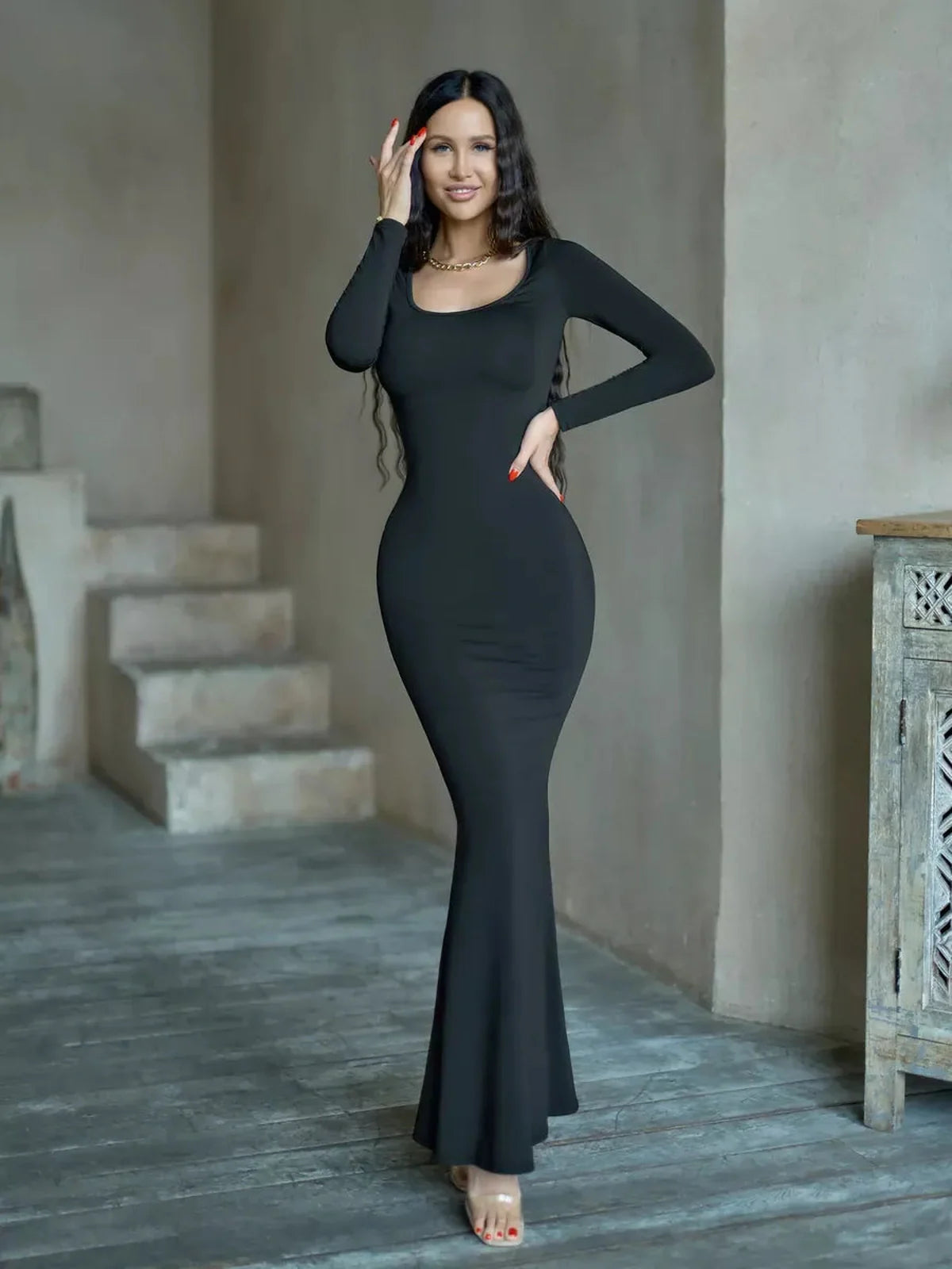 Model wearing the Sculpted Noir Maxi Dress, showcasing a sleek silhouette and long sleeves against a minimalist backdrop.