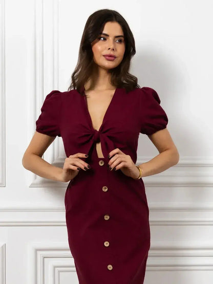 Model wearing the Maxi Dress Merlot Grace, featuring a front bow and button detail in a rich burgundy color.