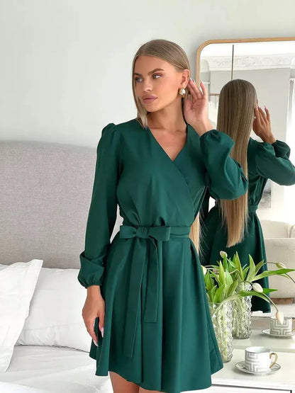 Model showcasing the Emerald Charm mini dress in emerald green, featuring a wrap-style bodice and elegant V-neckline.