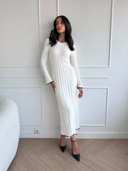 Model showcasing the Ivory Grace Maxi Dress featuring a sleek ribbed design and elegant ruffle trim for refined style.