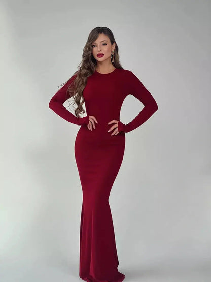Elegant model wearing a burgundy Velvet Ember Maxi Dress with long sleeves, showcasing a sleek silhouette and luxe stretch fabric.