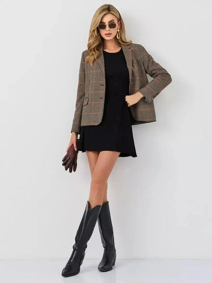 Chic woman in a black mini dress with a plaid blazer and knee-high black boots, styled for a fashionable autumn look.
