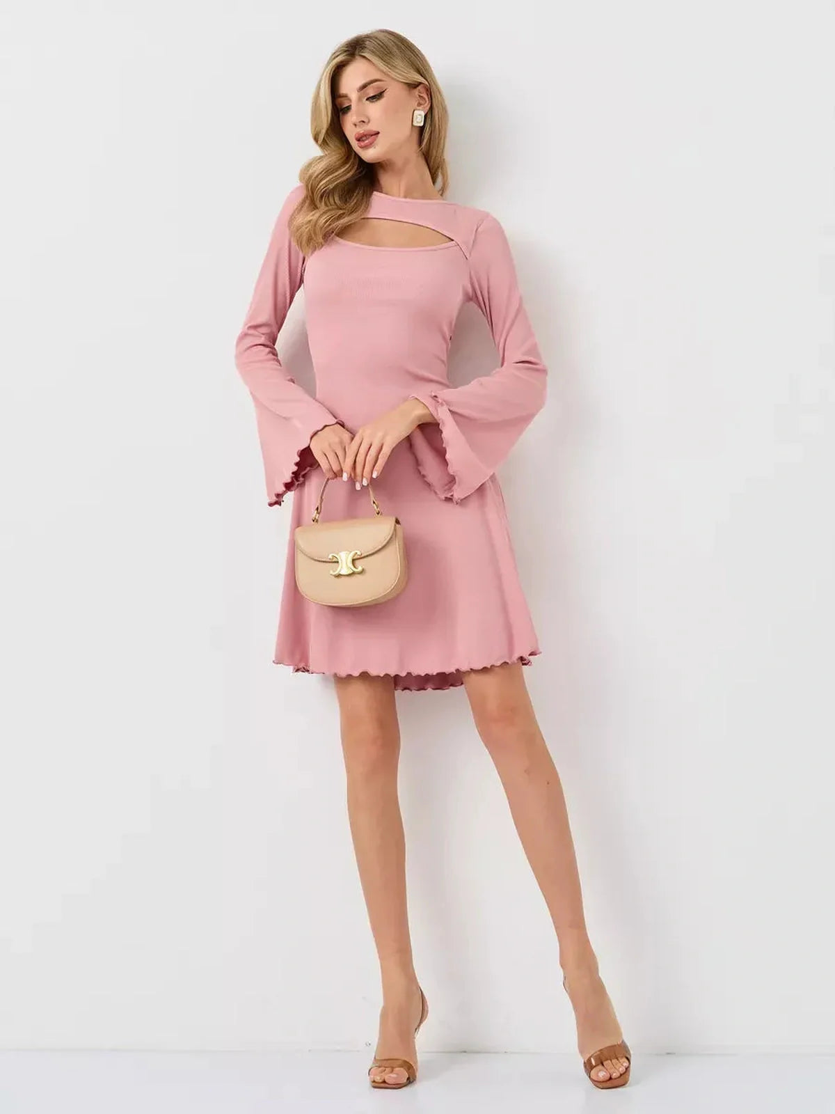 Model wearing a pink Blush Whisper dress with flared sleeves and a chic purse, showcasing summer elegance and feminine flair.