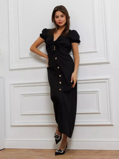 Elegant black maxi dress with tie-front detail and contrast buttons, featuring puff sleeves and a flattering V-neckline.