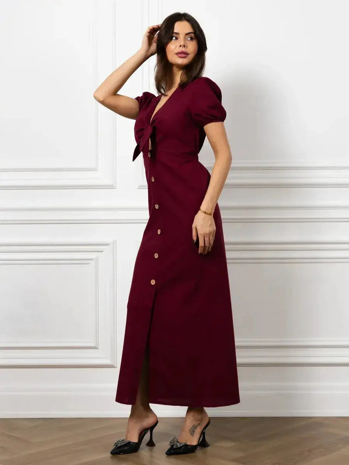 Elegant merlot maxi dress featuring a front bow, button detail, and structured puff sleeves, perfect for sophisticated occasions.