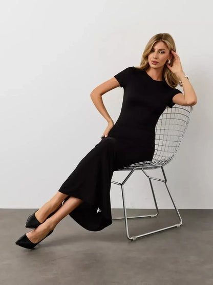 Model showcasing the Noir Curve Maxi Dress in iconic black, featuring a sculpted silhouette and flared hem.