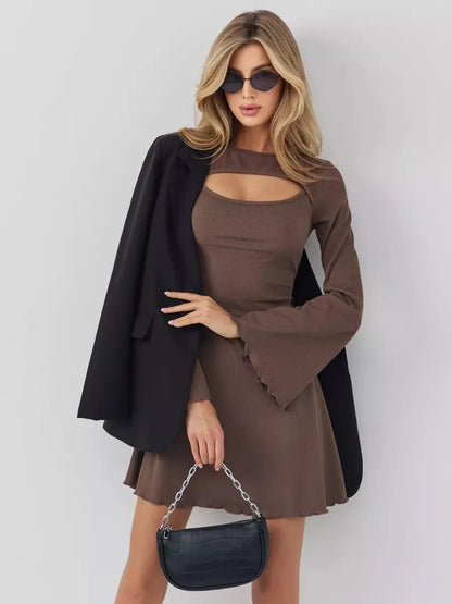 Elegant woman in a coffee hue mini dress with flared cuffs and chest cut-out, styled with sunglasses and a blazer.