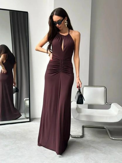 Model in a sleek sienna maxi dress featuring a halter neckline and front slit, showcasing elegant ruching and modern style.
