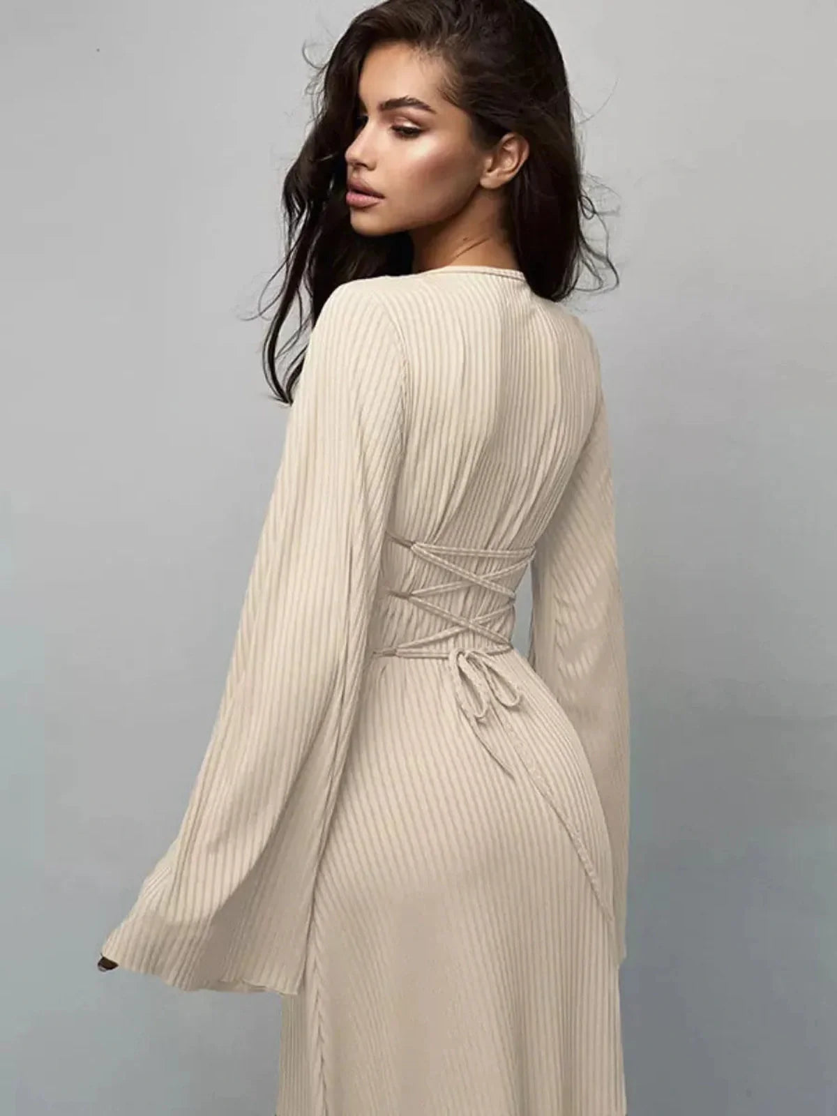 Stylish woman showcasing the back of the Sculpted Elegance Maxi Dress with a lace-up feature and elegant bell sleeves.