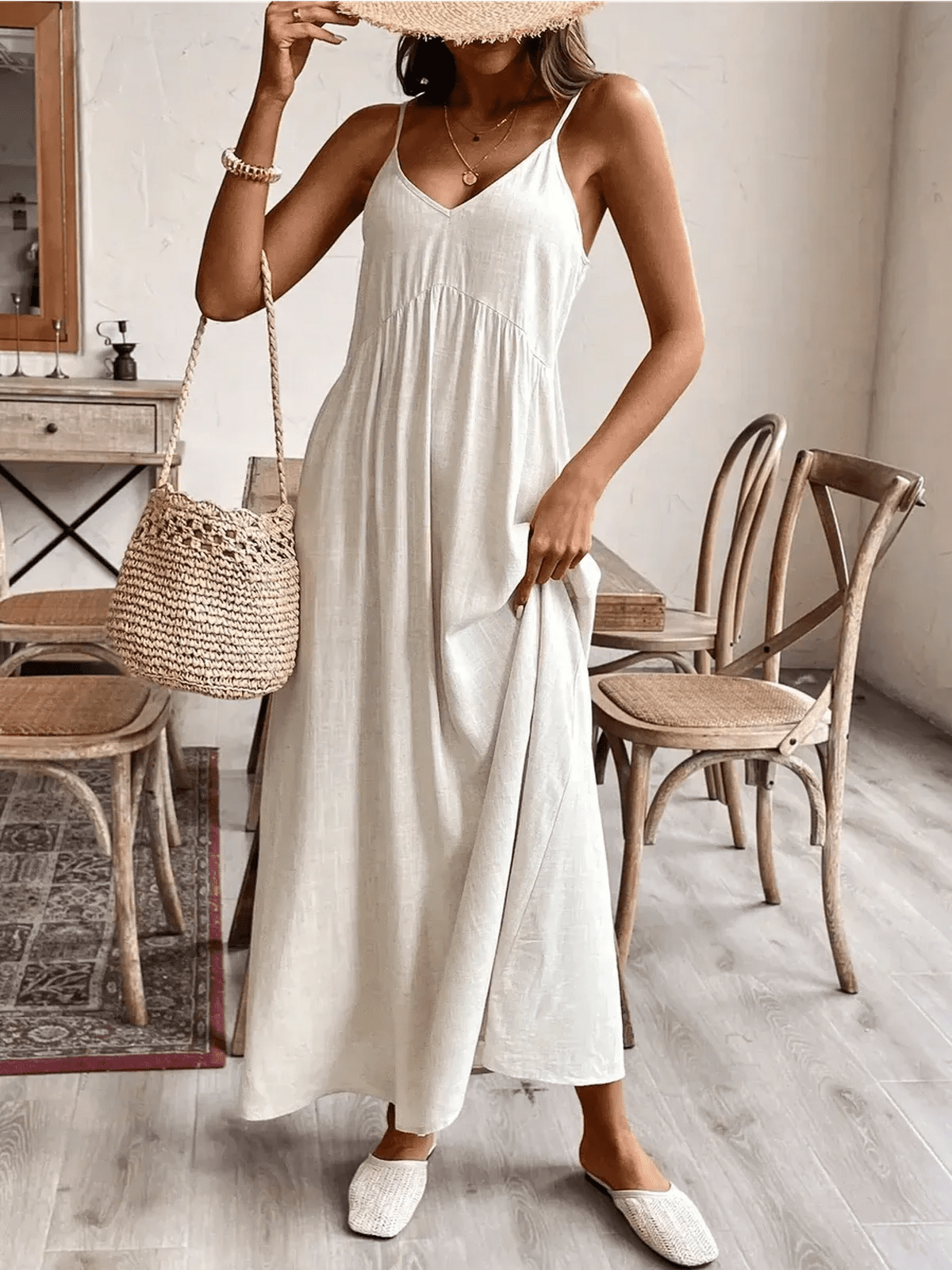 Model wearing a lightweight Serenity Maxi Dress in a soft hue, styled with a woven bag in a chic indoor setting.