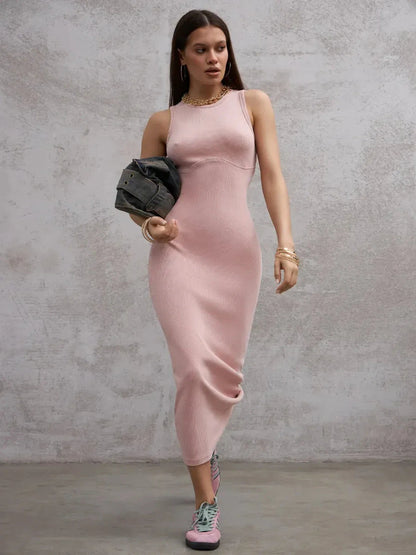 Model wearing a fitted blush pink maxi dress with a sleeveless design, styled for a modern romantic look.