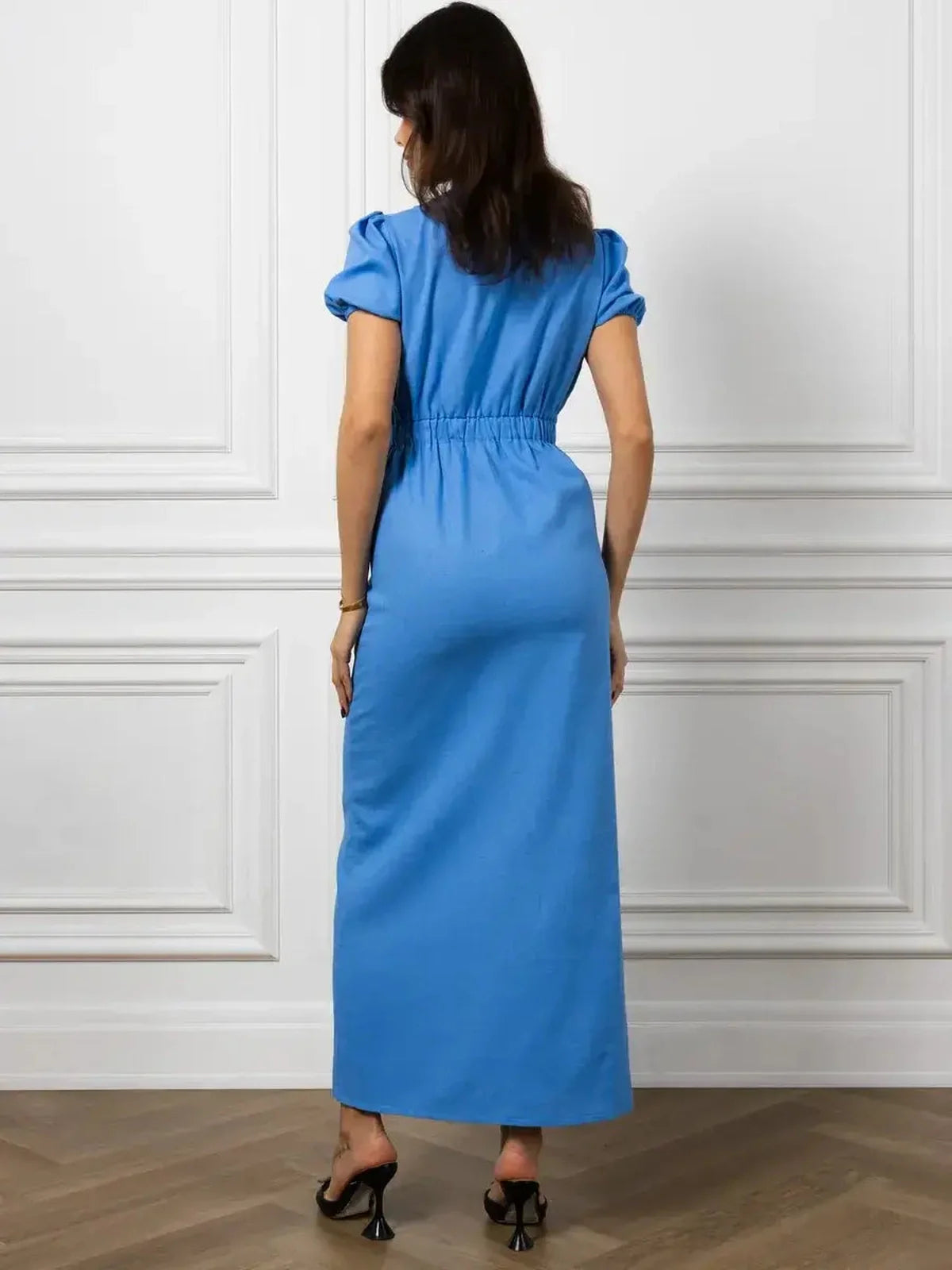 Back view of a woman in an azure maxi dress featuring a V-neck and puff sleeves, showcasing elegant style.