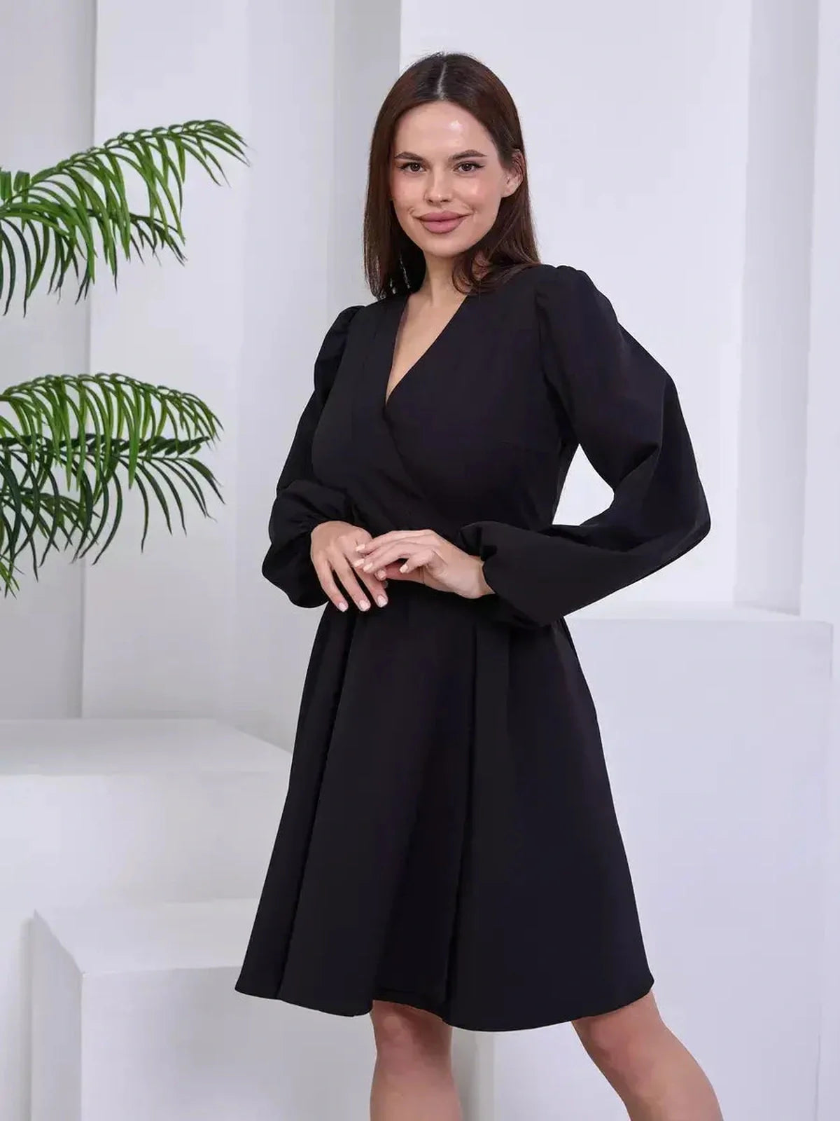 Model showcasing the Midnight Sway black mini dress with long sleeves and a wrap silhouette, exuding timeless elegance.