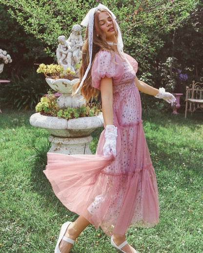 Model wearing a flowy pink maxi dress with a mesh overlay, perfect for summer occasions and weddings.