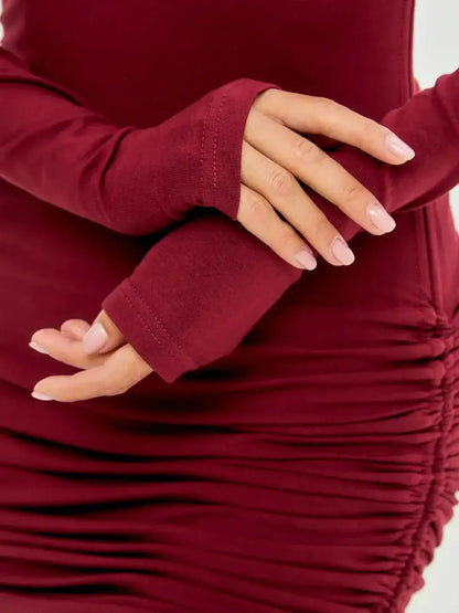 Close-up of a woman's hands in burgundy long sleeve dress with ruched detailing.