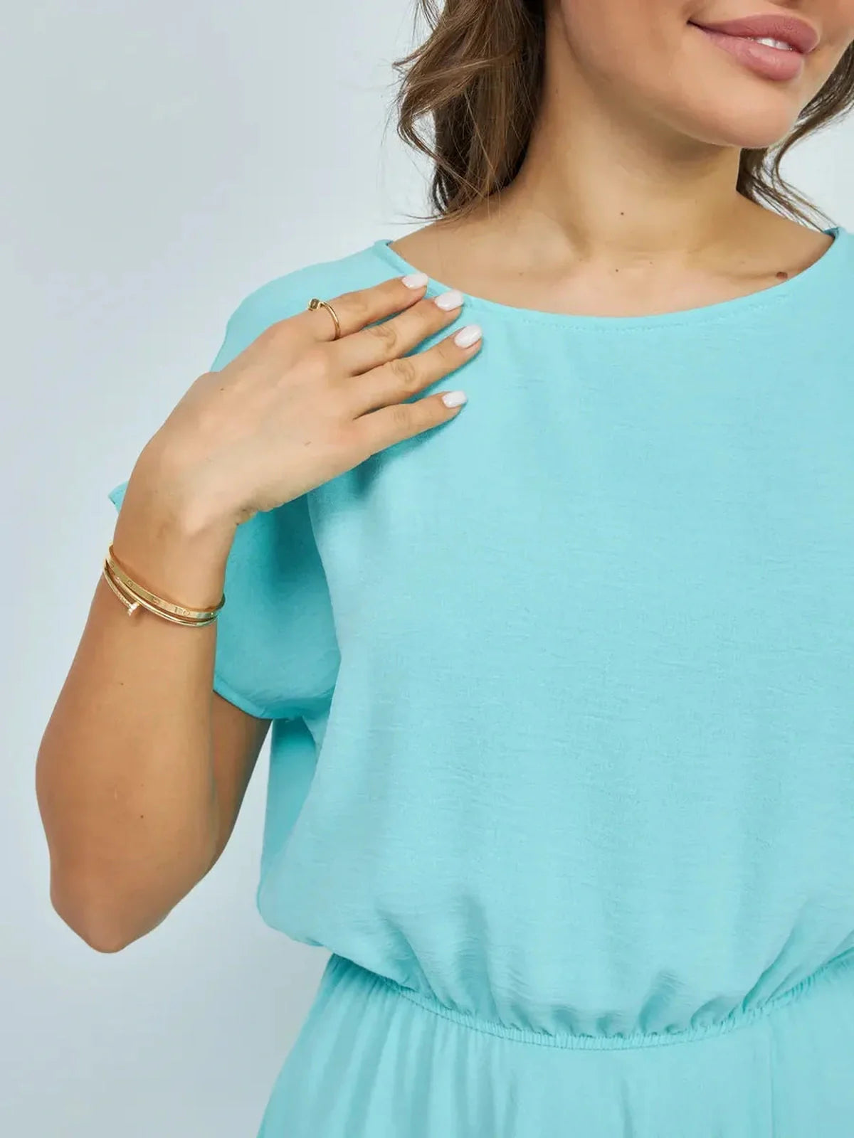 Detail of a woman wearing a light blue dress with an elastic waist, showcasing a relaxed fit and elegant style.