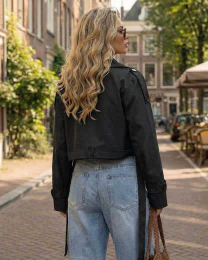 Noir Jacket by Lauven – Women's black cropped trench jacket styled outdoors with a scenic background.