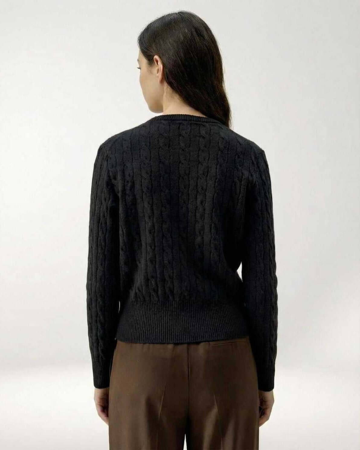 Back view of a woman wearing the Monaco Cardigan, a black cable knit sweater by Lauven.