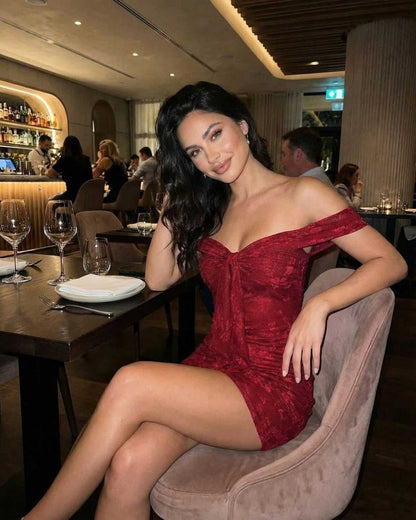 Verona Mini Dress by Lauven, showcasing an off-the-shoulder design in elegant red jacquard at a stylish dinner setting.