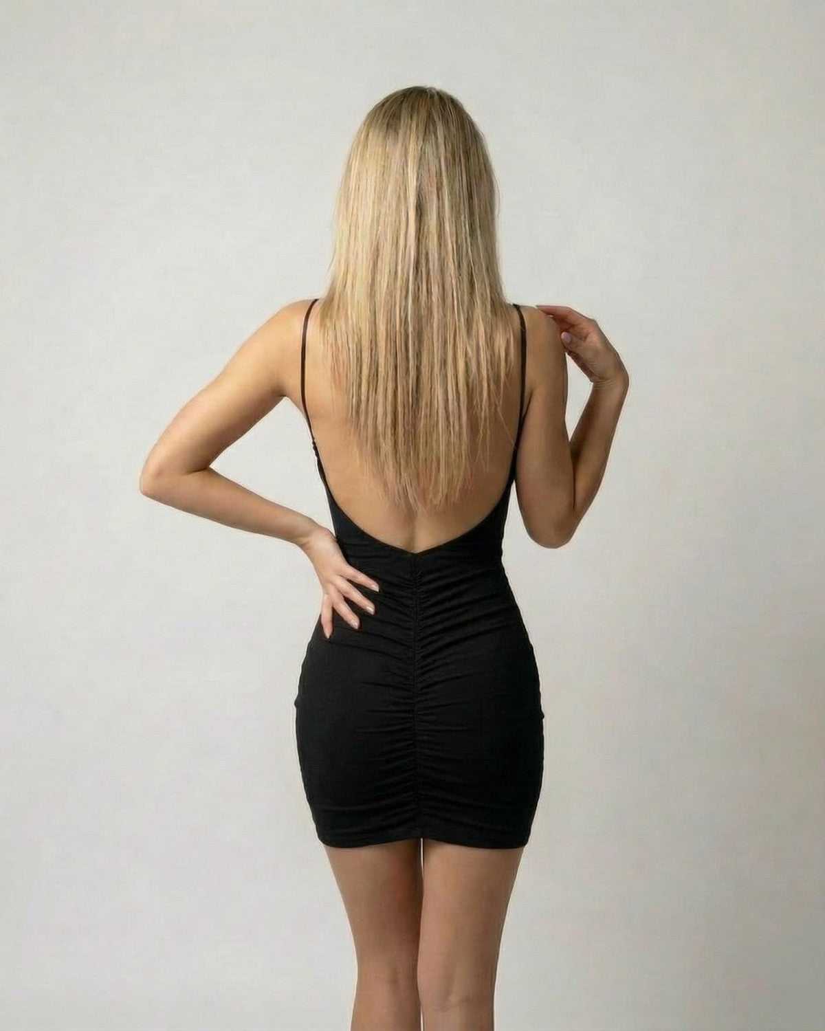 Model wearing the Lauven Noir Mini Dress: a sleek high-waist, sleeveless black mini dress with a V-neck silhouette.