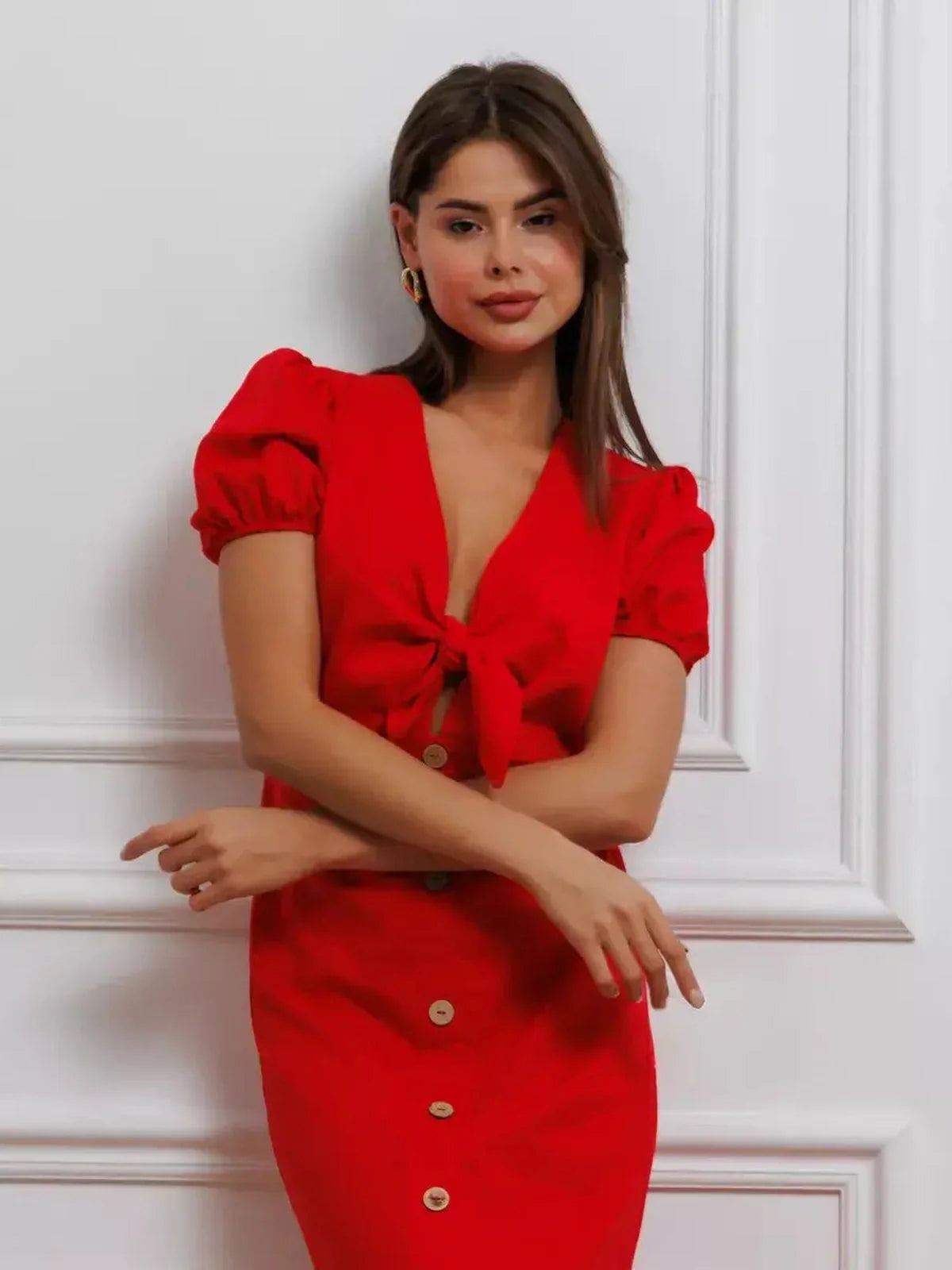 Model wearing a bold red maxi dress with tie-front and puff sleeves, showcasing sophisticated elegance.