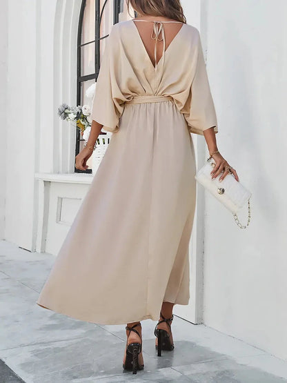 Back view of Serene Elegance Maxi Dress with flowing silhouette, waist tie, and deep V-neckline in a soft beige color.