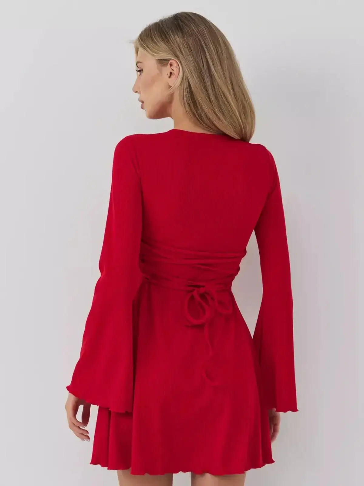 Model wearing a stunning red Velvet Flame mini dress with bell sleeves and a tied back design, perfect for summer and wedding guests.