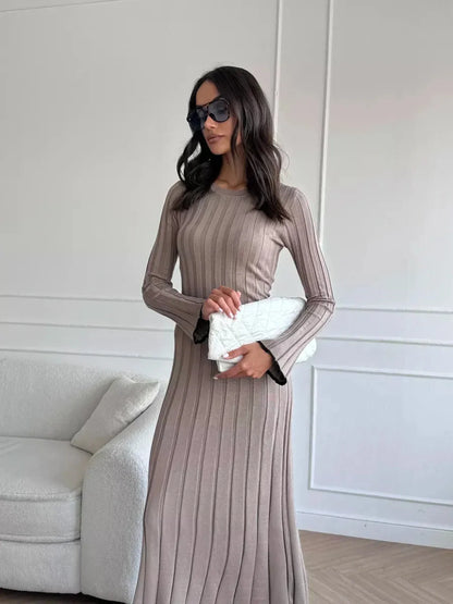 Woman wearing a ribbed knit Contour Maxi Dress with long sleeves and sunglasses, holding a chic clutch.