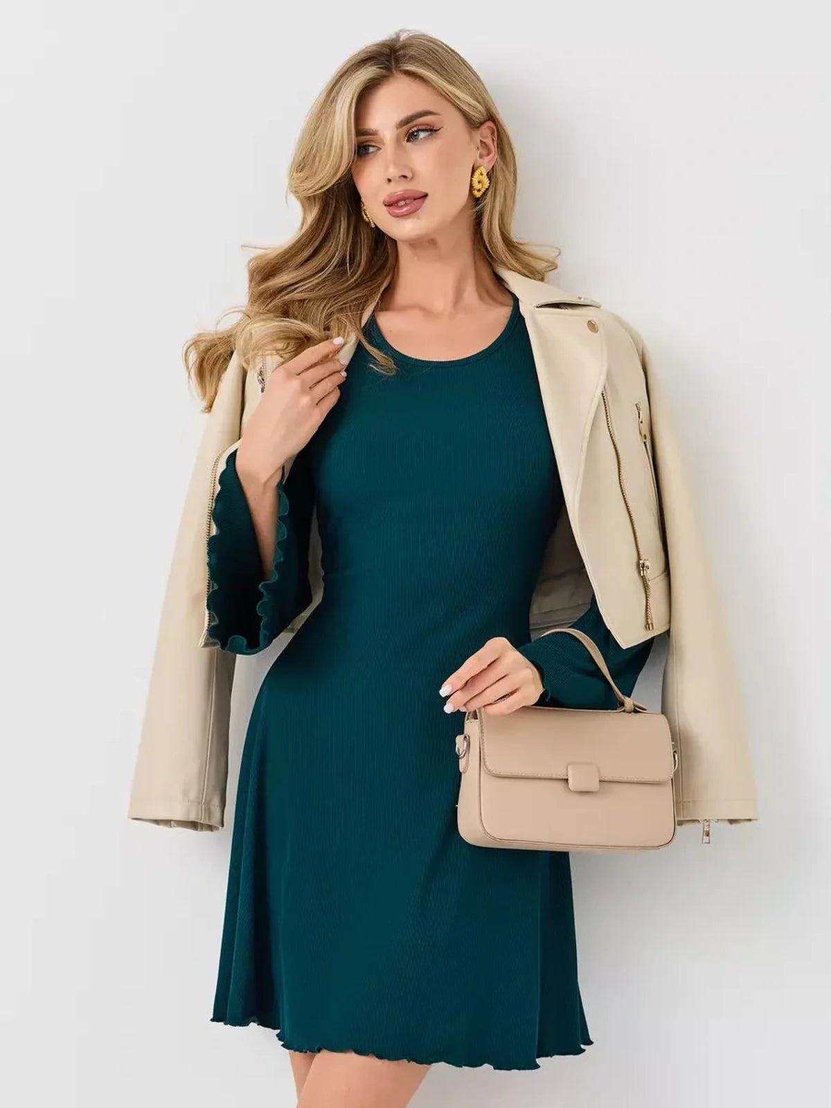 Model wearing the Emerald Whisper mini dress in emerald green, styled with a cream jacket and handbag.
