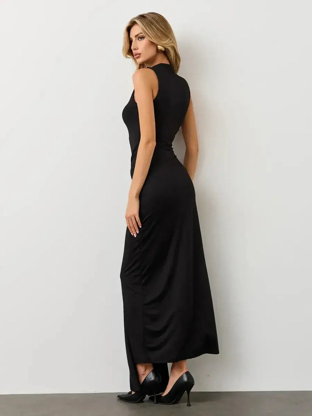 Woman wearing an elegant sleeveless black Obsidian Drape Maxi Dress showcasing a sculpted silhouette and knotted draping.