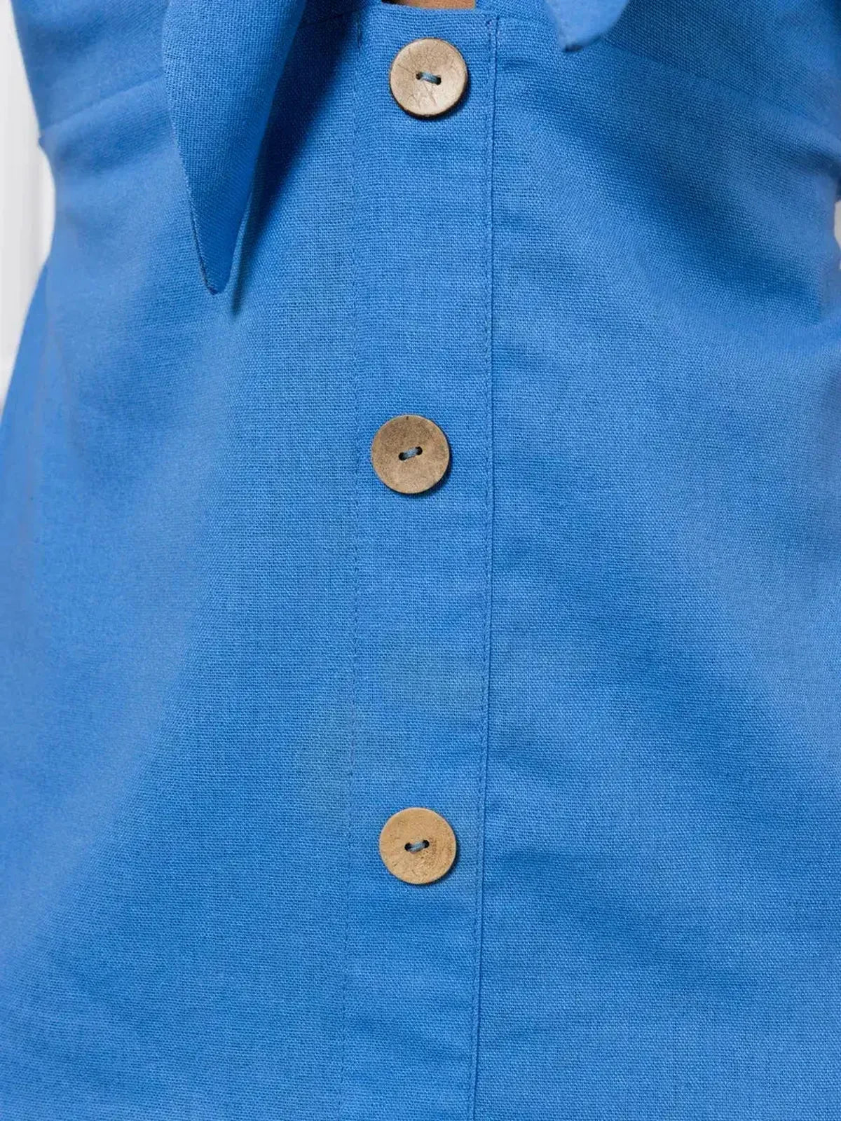 Detail of button closure on a sky-blue maxi dress, showcasing the tie-front and elegant fabric texture.