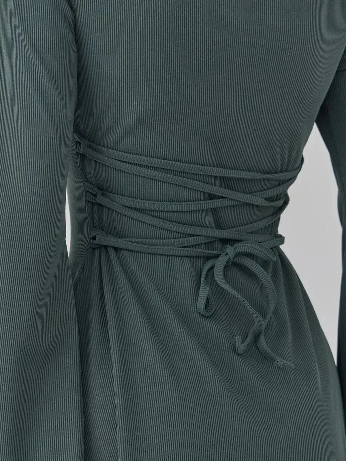 Close-up of dark olive mini dress showing waist-defining lace-up ties for stylish fitted look.
