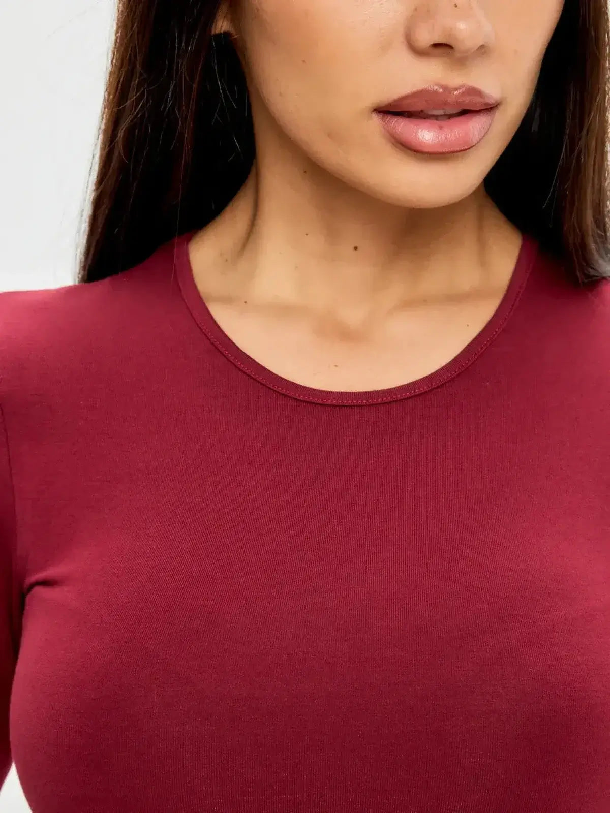 Close-up of a model wearing a burgundy long sleeve mini dress with a smooth silhouette.