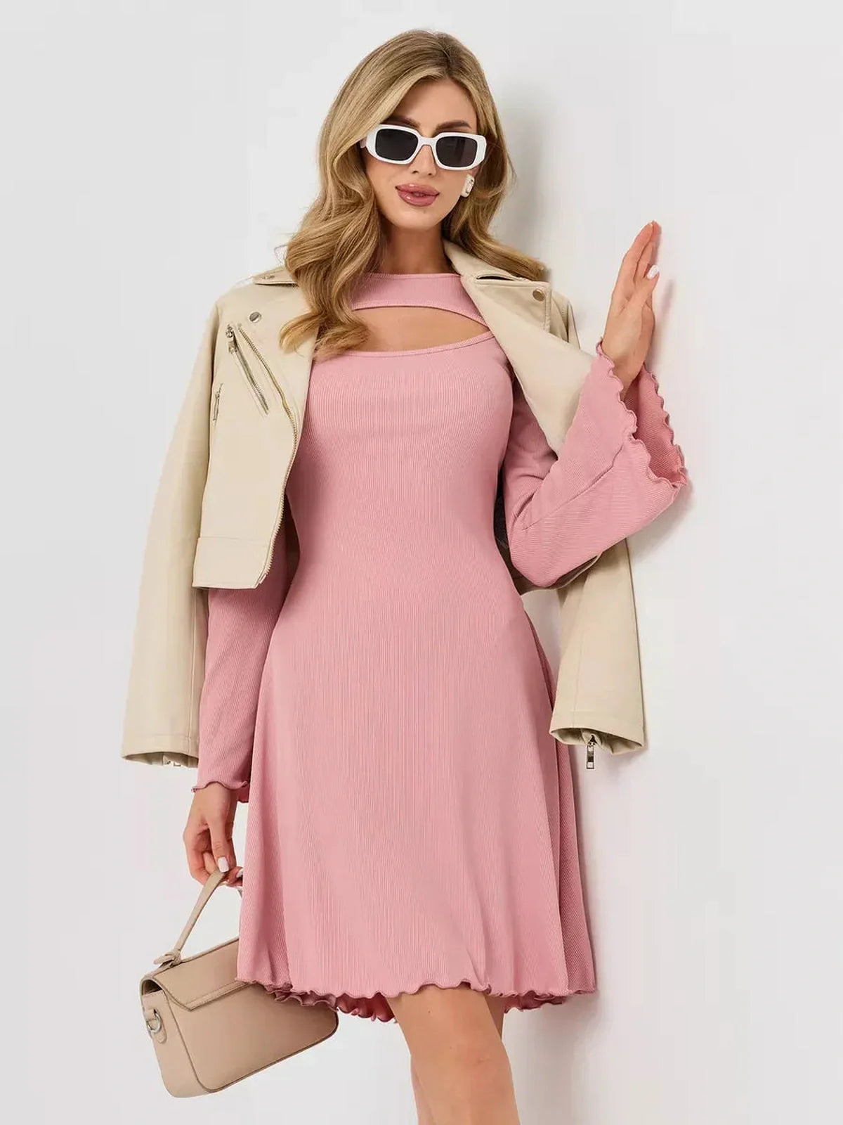 Woman in a pink ribbed knit dress with U-neckline and flared sleeves, wearing a beige jacket and sunglasses.