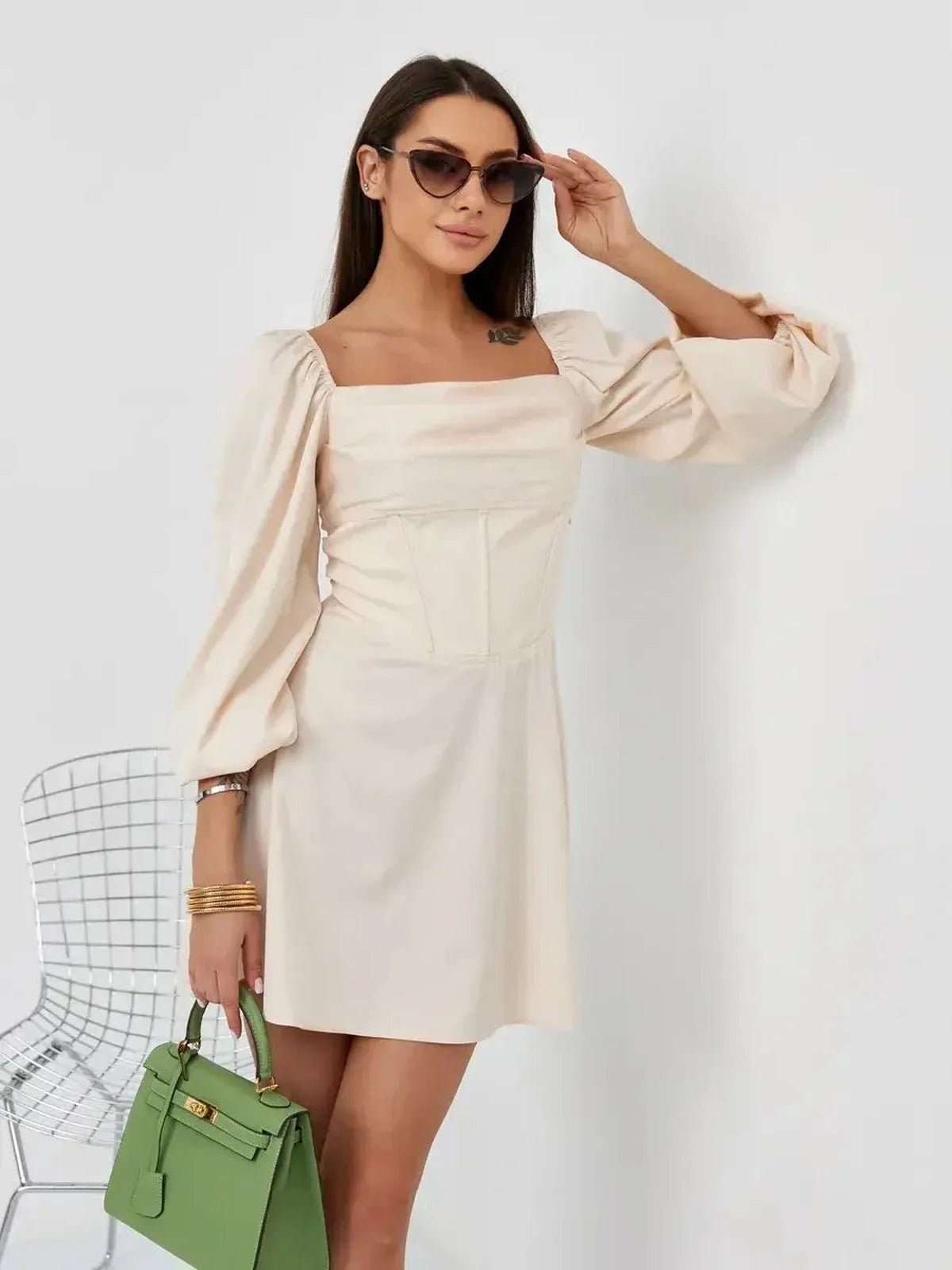 Model wearing a beige Lace Muse mini dress with puffed sleeves and square neckline, showcasing effortless elegance.