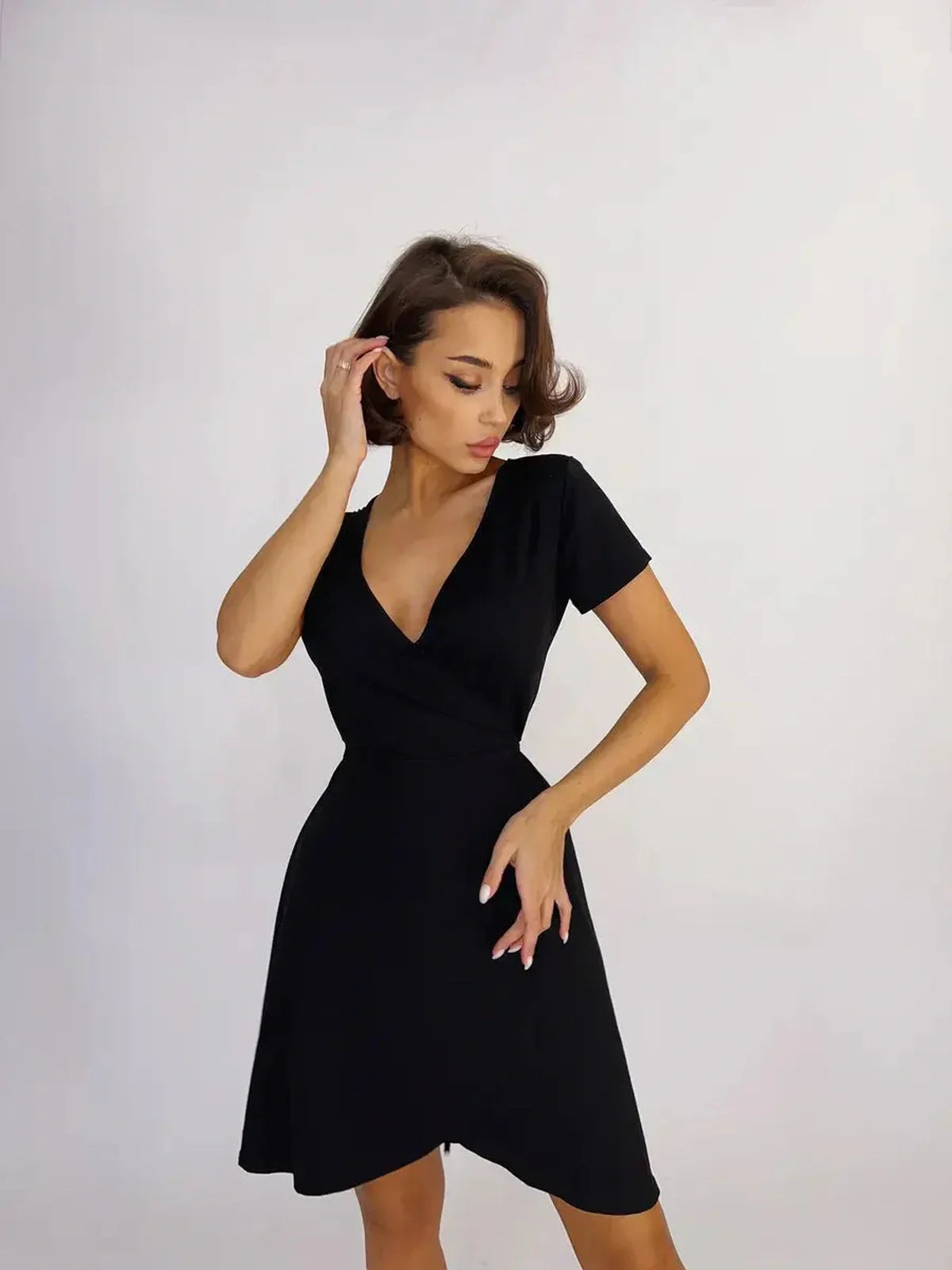 Sleek black mini dress featuring a deep V-neckline and fitted wrap design for effortless allure.